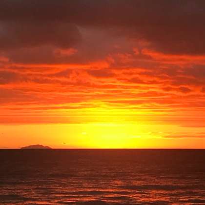 Nos Creemos Algo cover — orange sunset over a dark sea